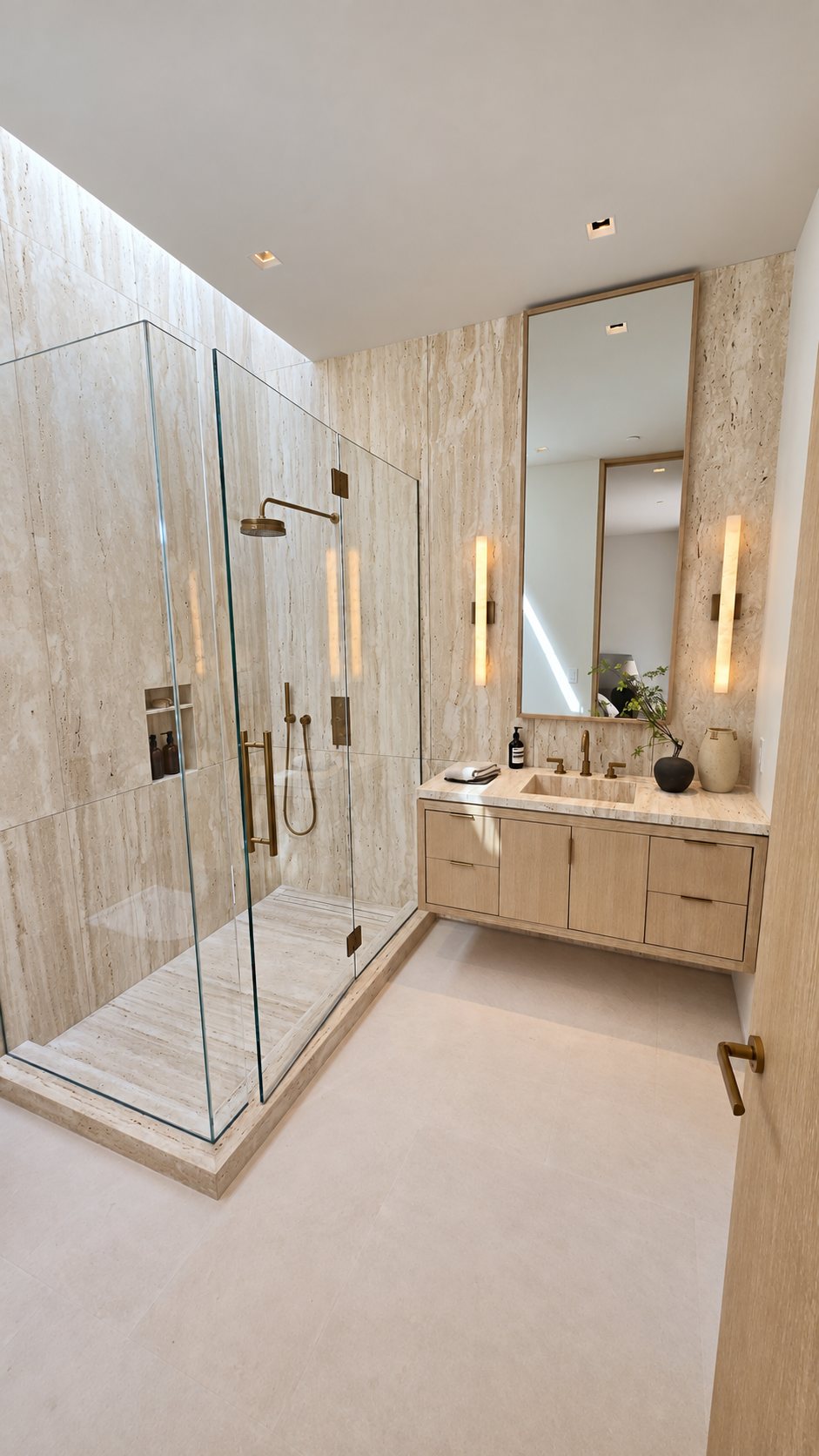 Bathroom remodel in Brentwood: travertine walls and shower, frameless glass enclosure, floating oak vanity and brass fittings